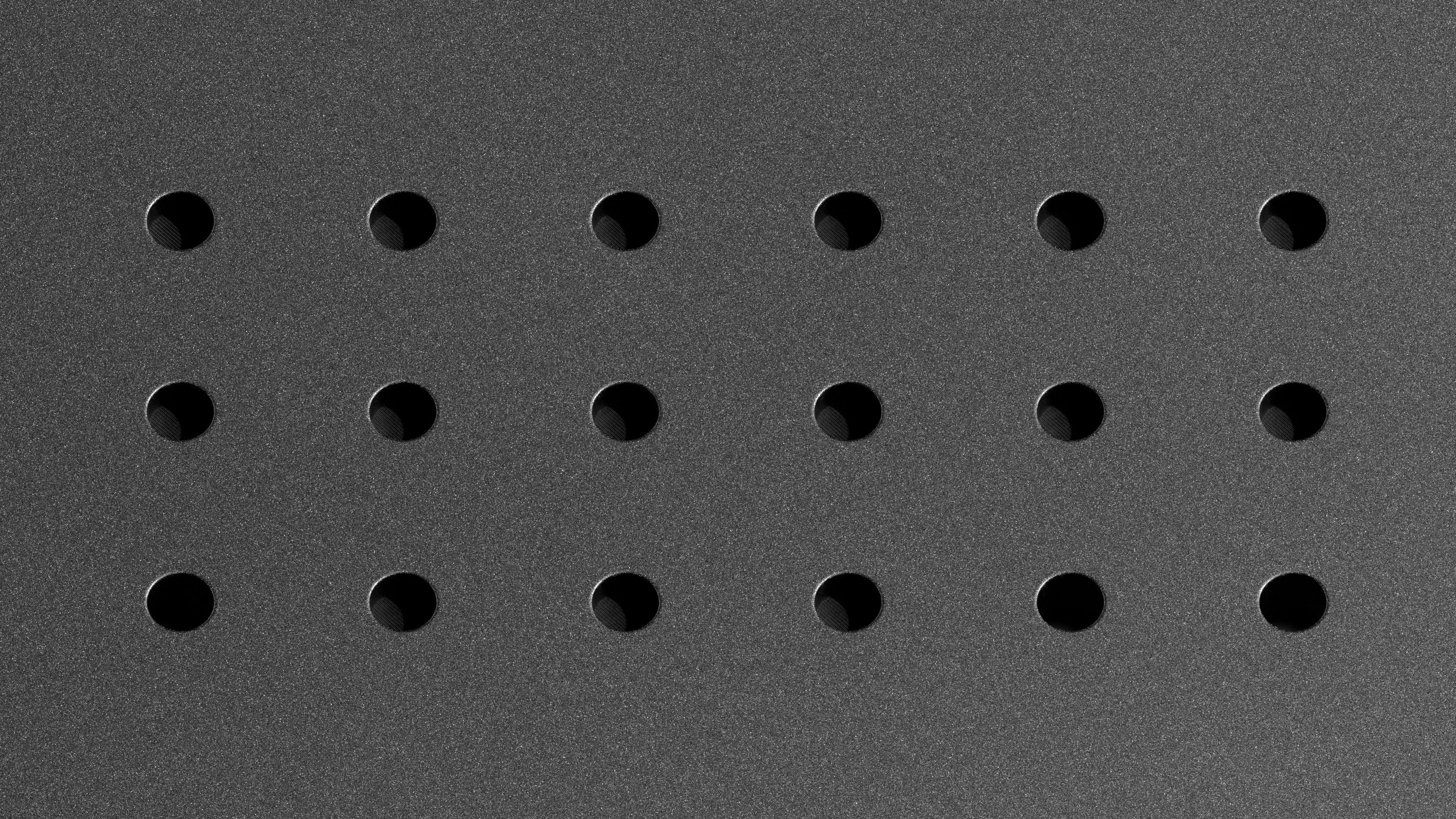 Close-up of the Huddly C1 microphone array, featuring a grid of small circular openings on the device’s dark matte surface.